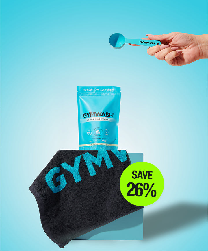 Gym wash product with a black towel and a hand holding a measuring spoon on a blue background